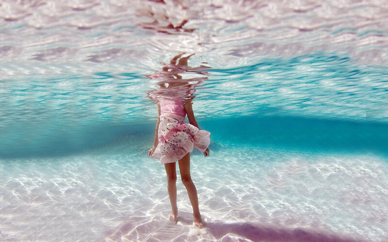 child underwater in pink dress