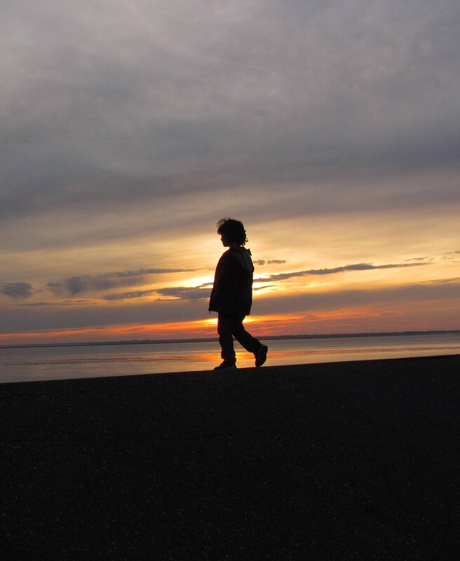Child walking on beach at sunset