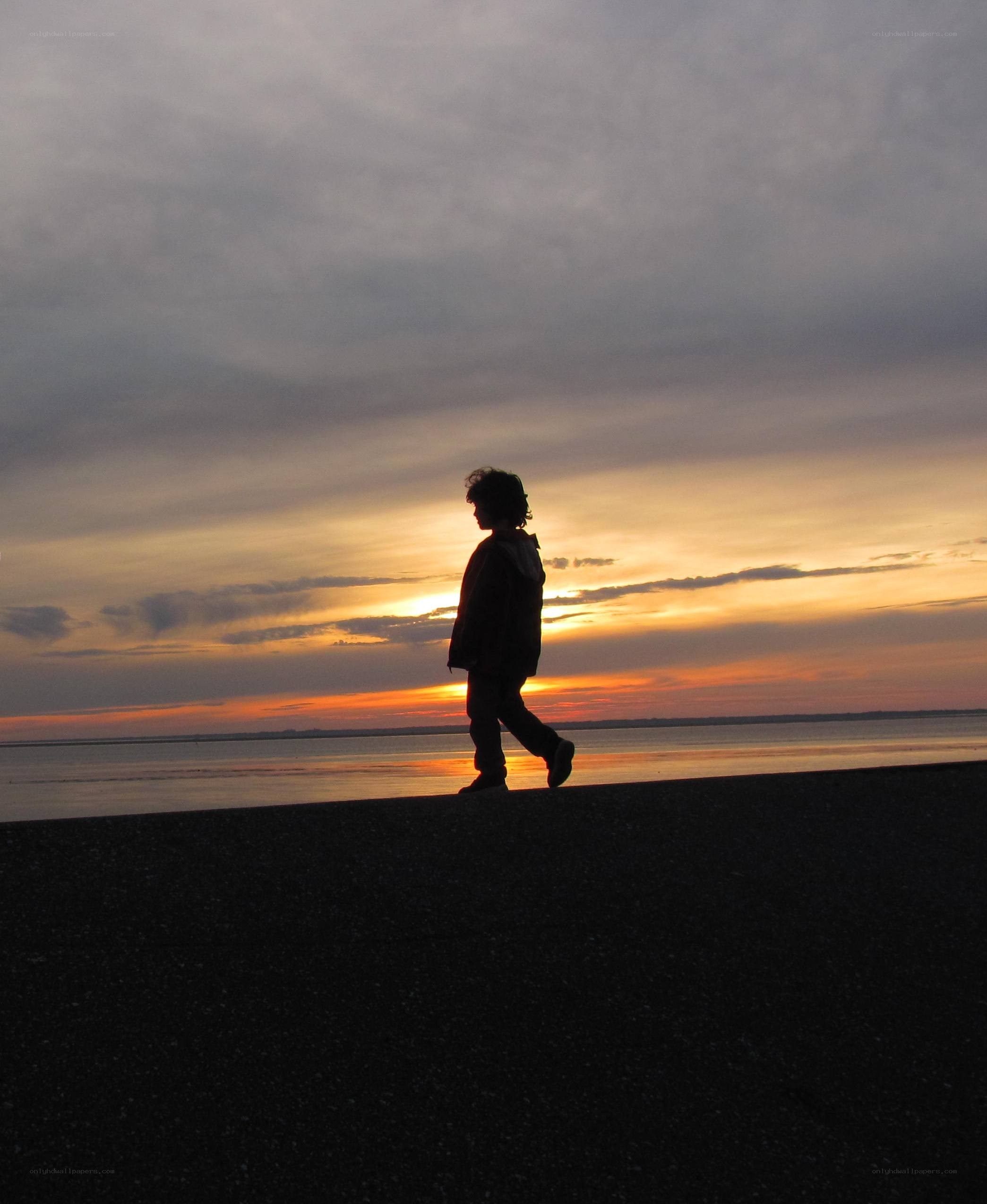 Child walking on beach at sunset