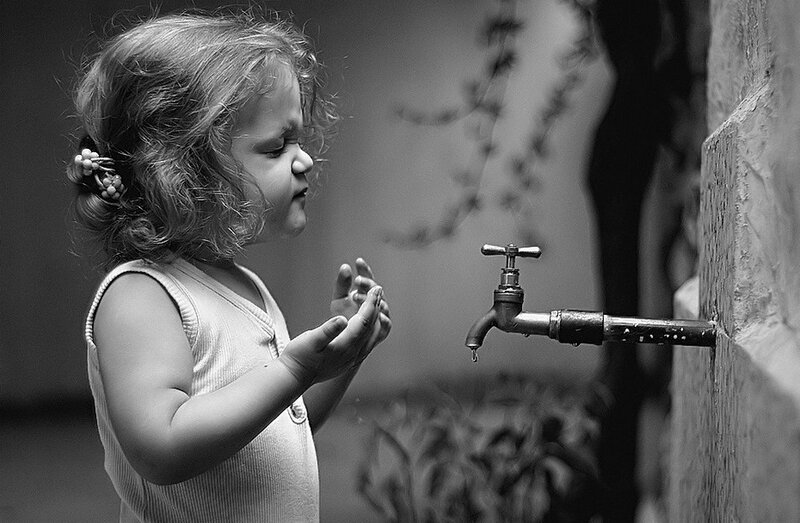 child washing hands at faucet
