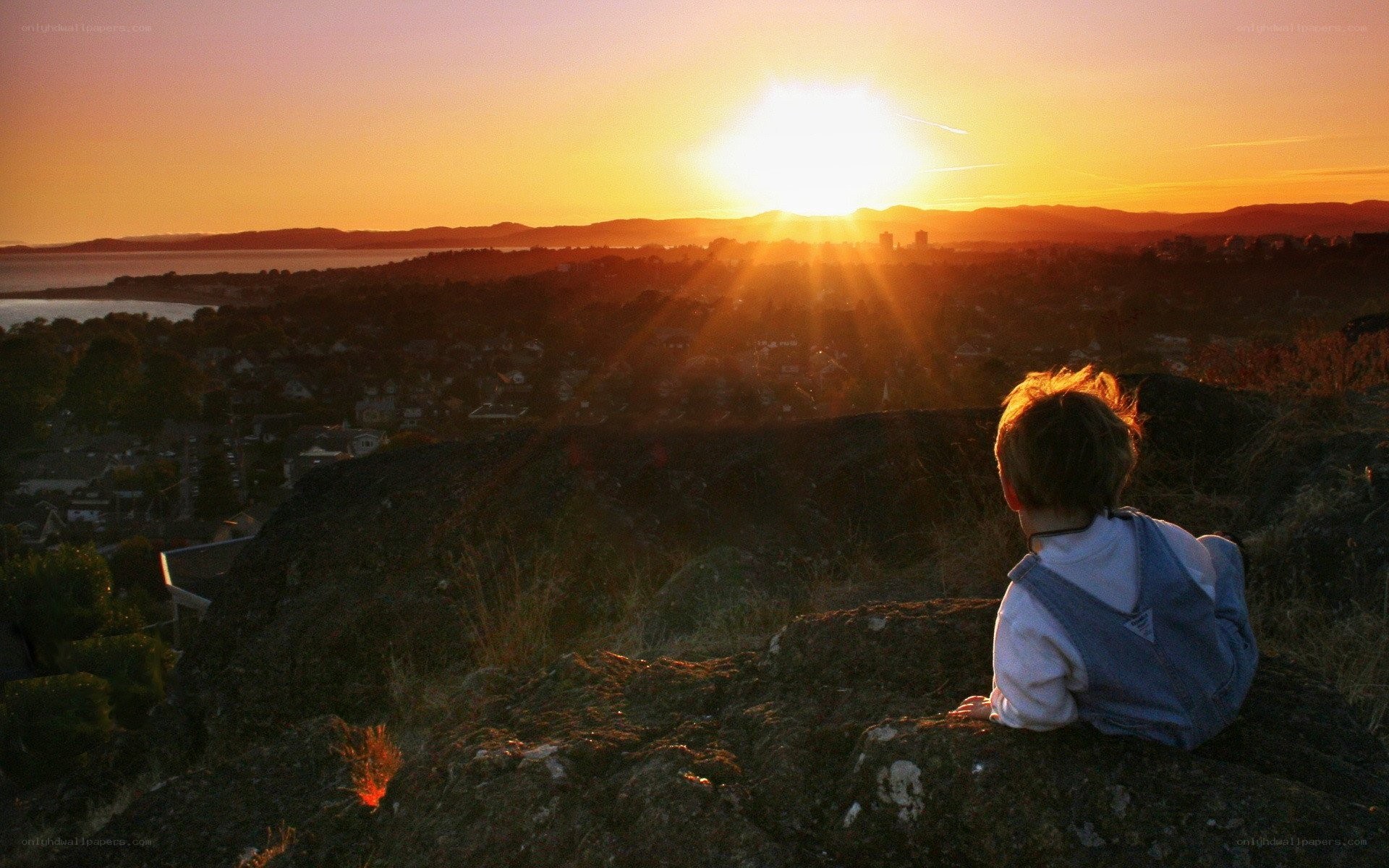child watching sunset over town
