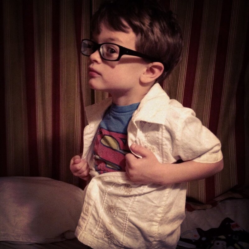 child wearing glasses and superman shirt