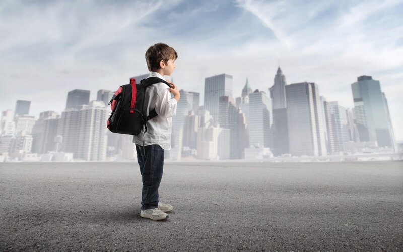 child with backpack in city