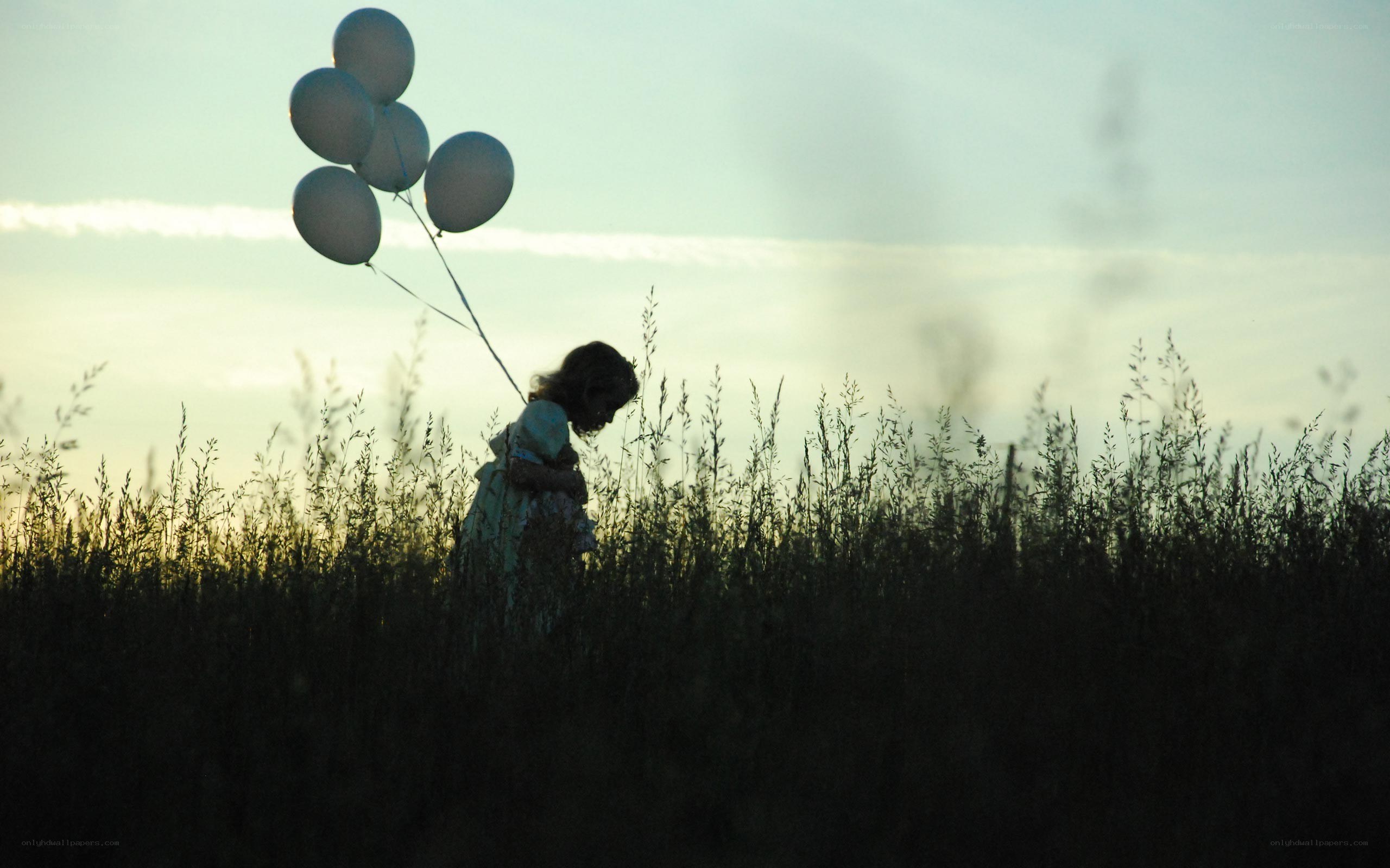 Child with balloons in field