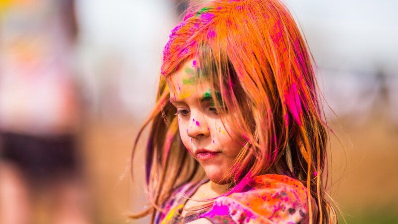 child with colorful paint on face