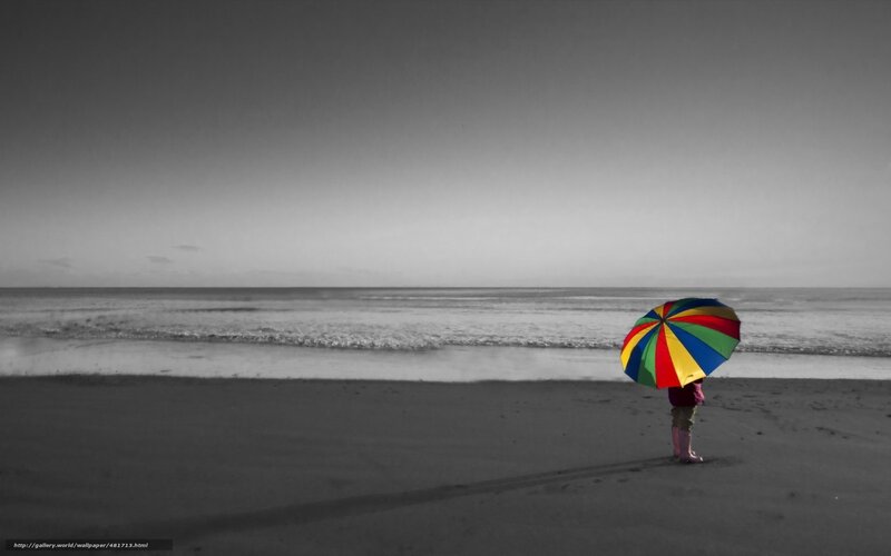 Child with colorful umbrella on beach