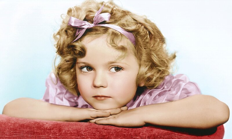 child with curly hair and pink bow