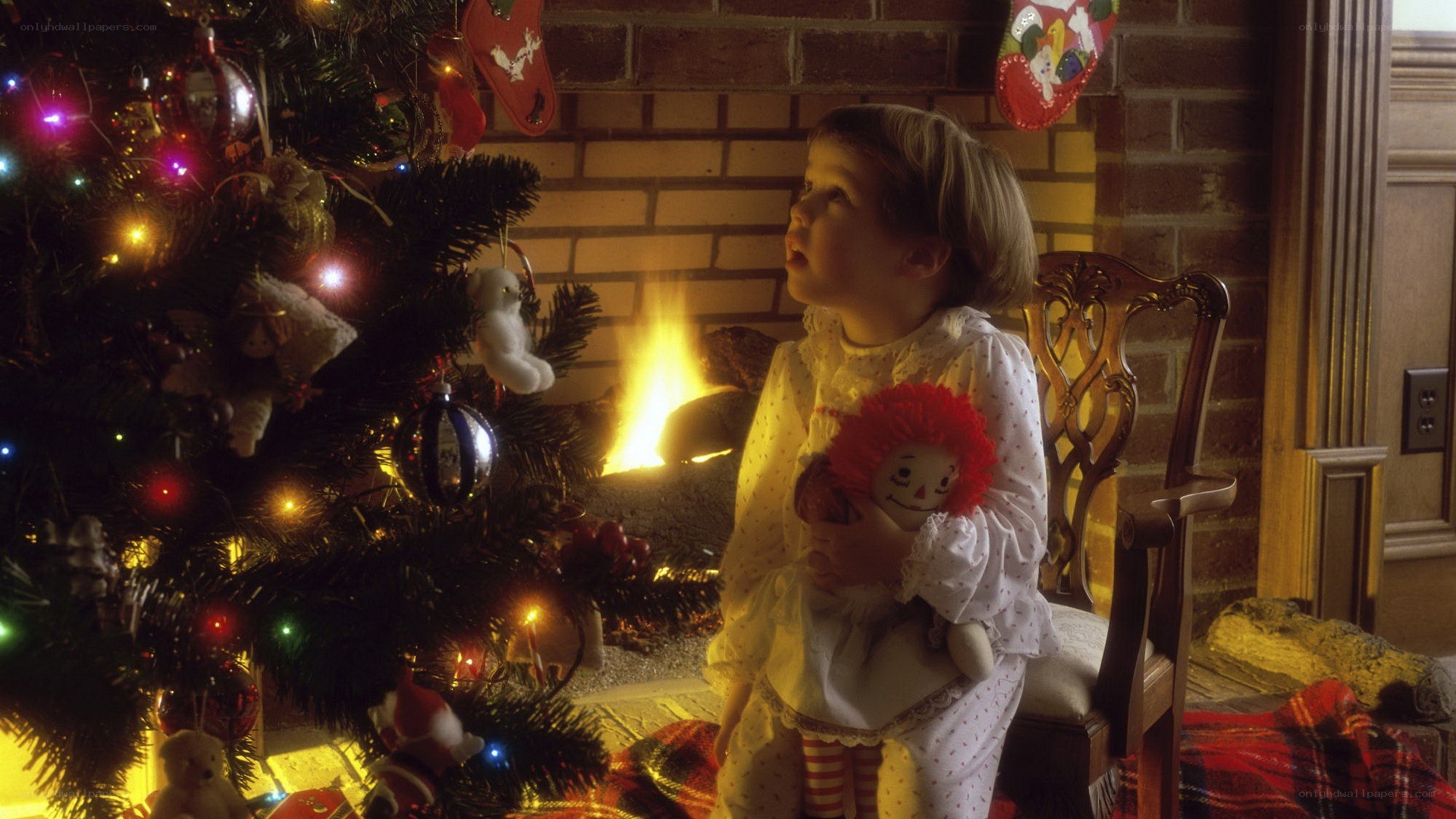 child with doll by Christmas tree