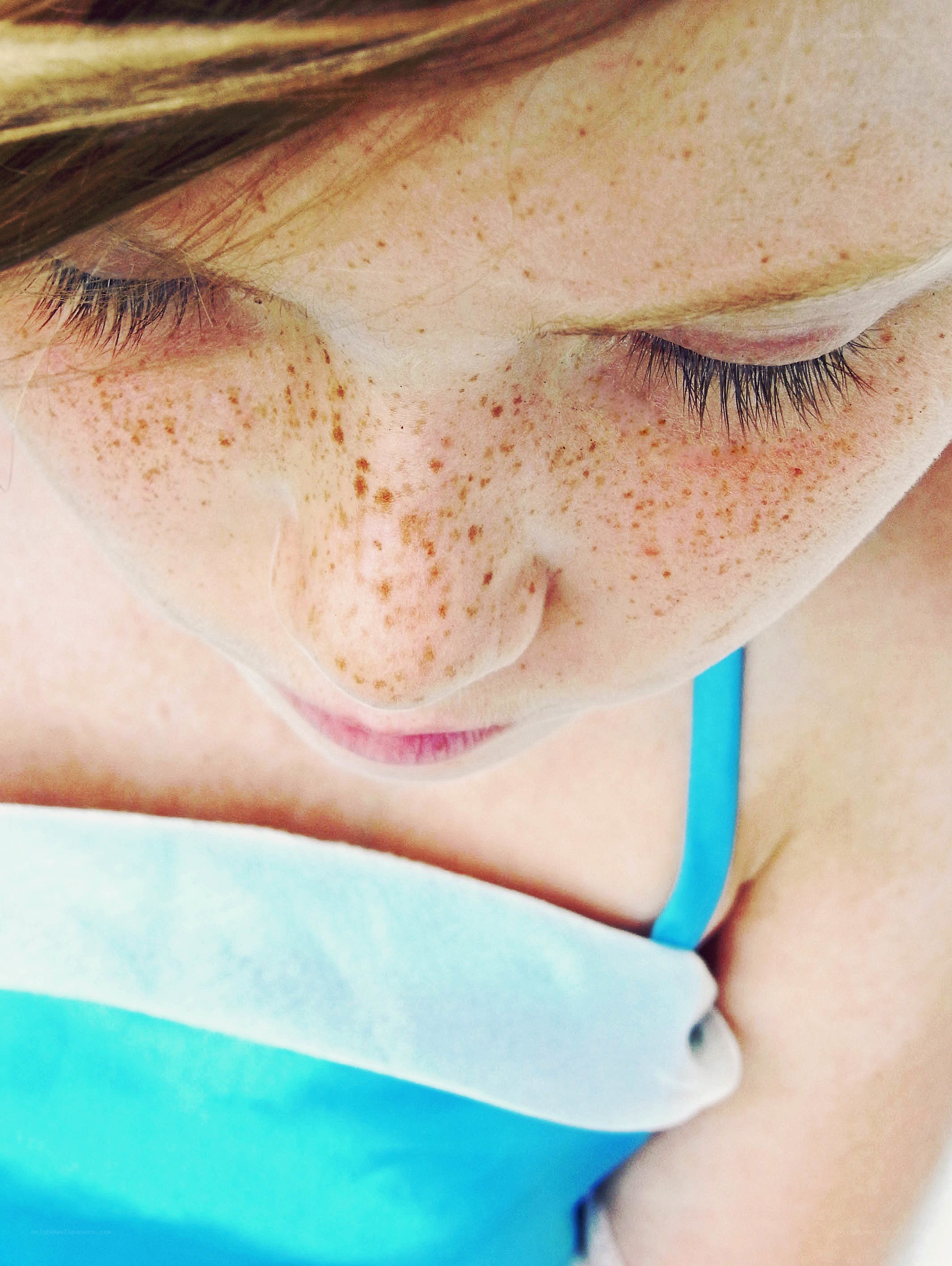 child with freckles looking down