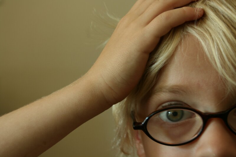 child with glasses touching head