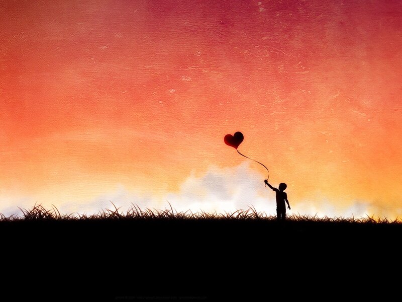 Child with heart balloon at sunset