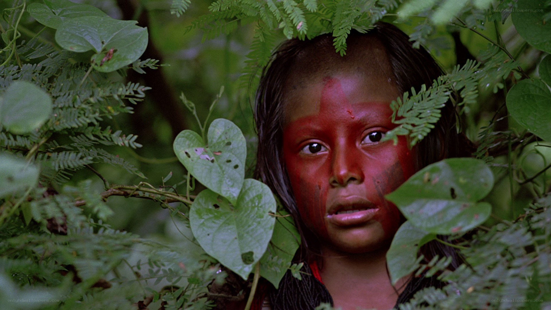 child with red face paint in jungle