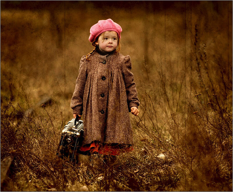 child with suitcase in field