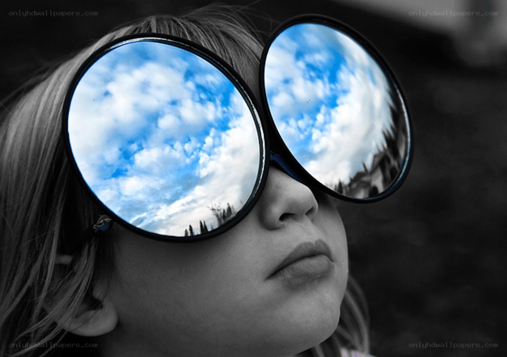child with sunglasses reflecting sky