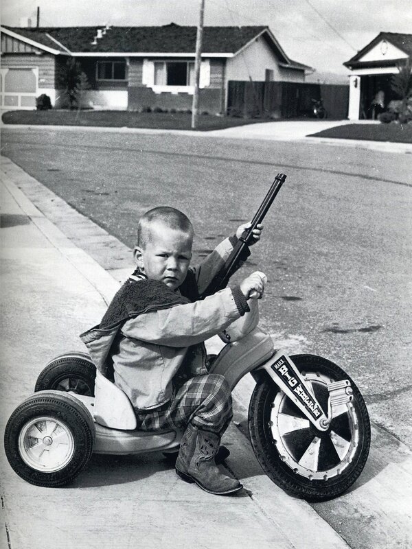 Child with toy gun on tricycle