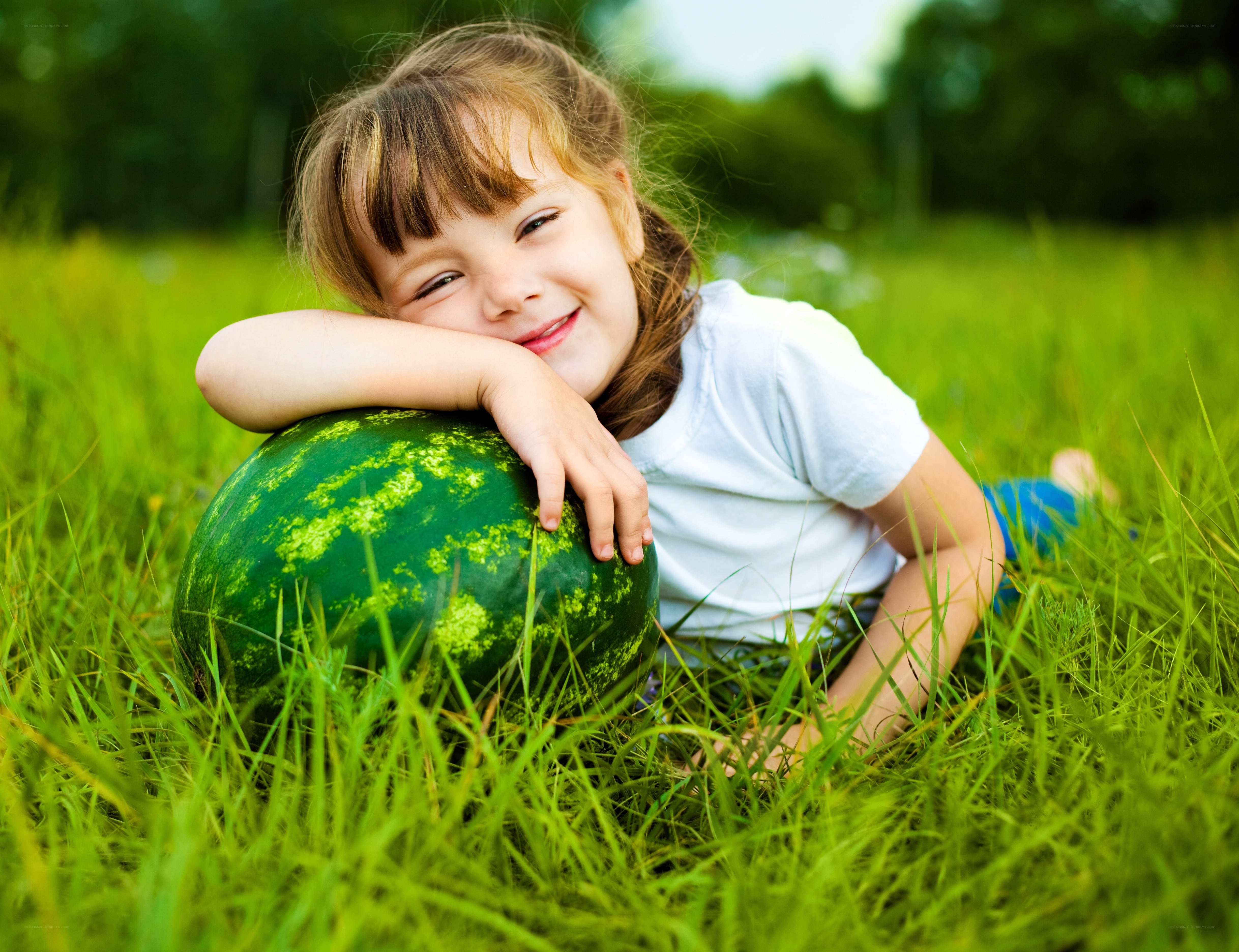 child with watermelon in grass