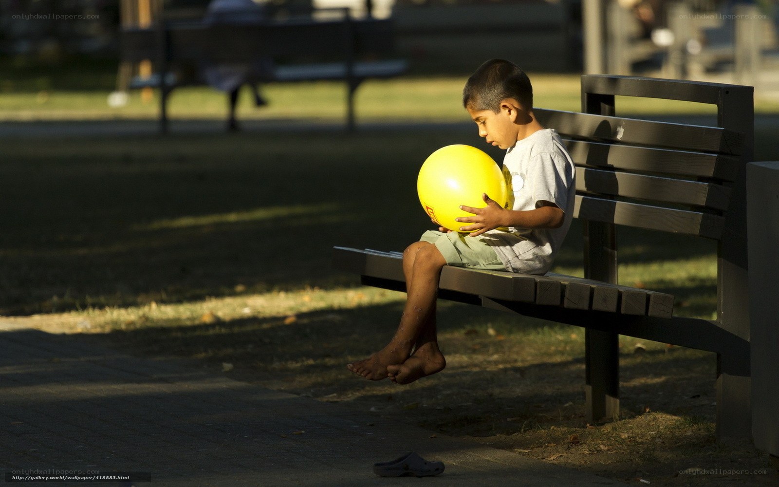Child with yellow ball on bench