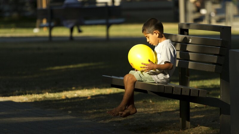 Child with yellow ball on bench
