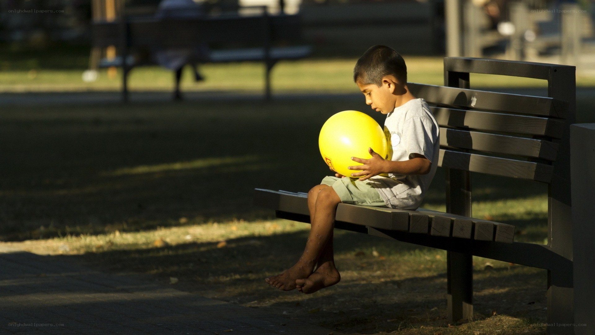 Child with yellow ball on bench