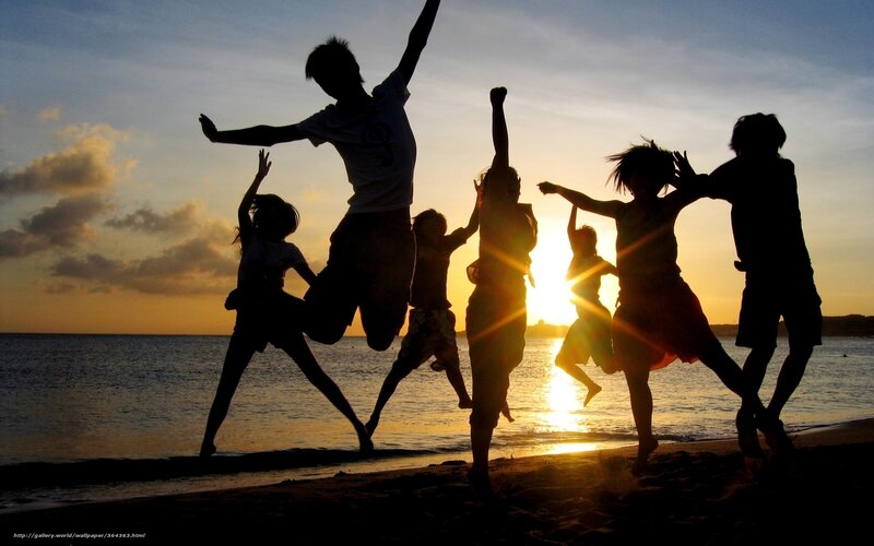 Children jumping on the beach at sunset