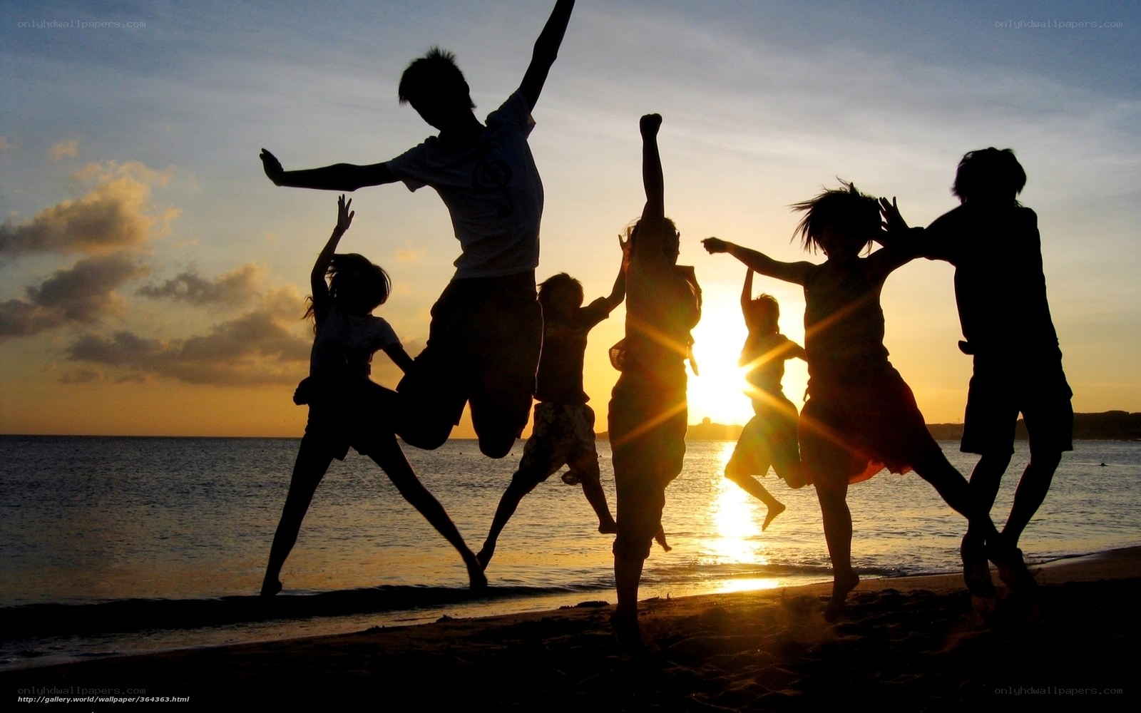 Children jumping on the beach at sunset