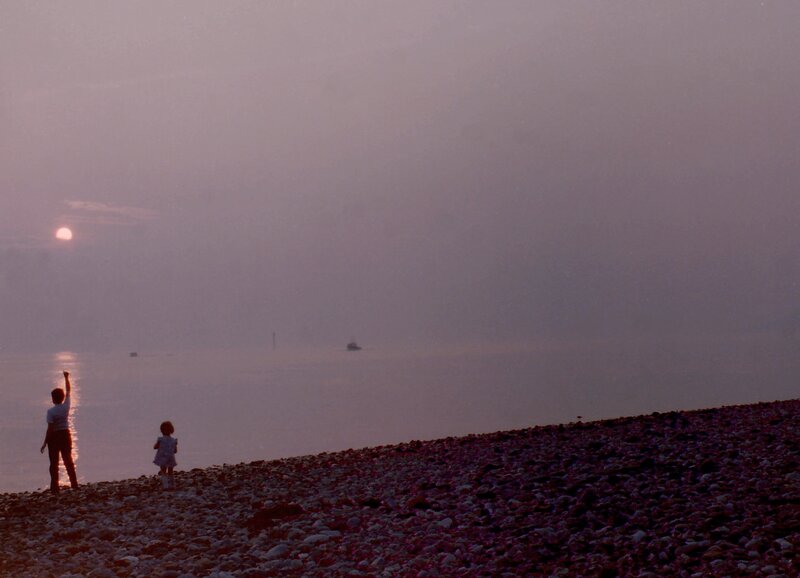 Children on a pebble beach at sunset