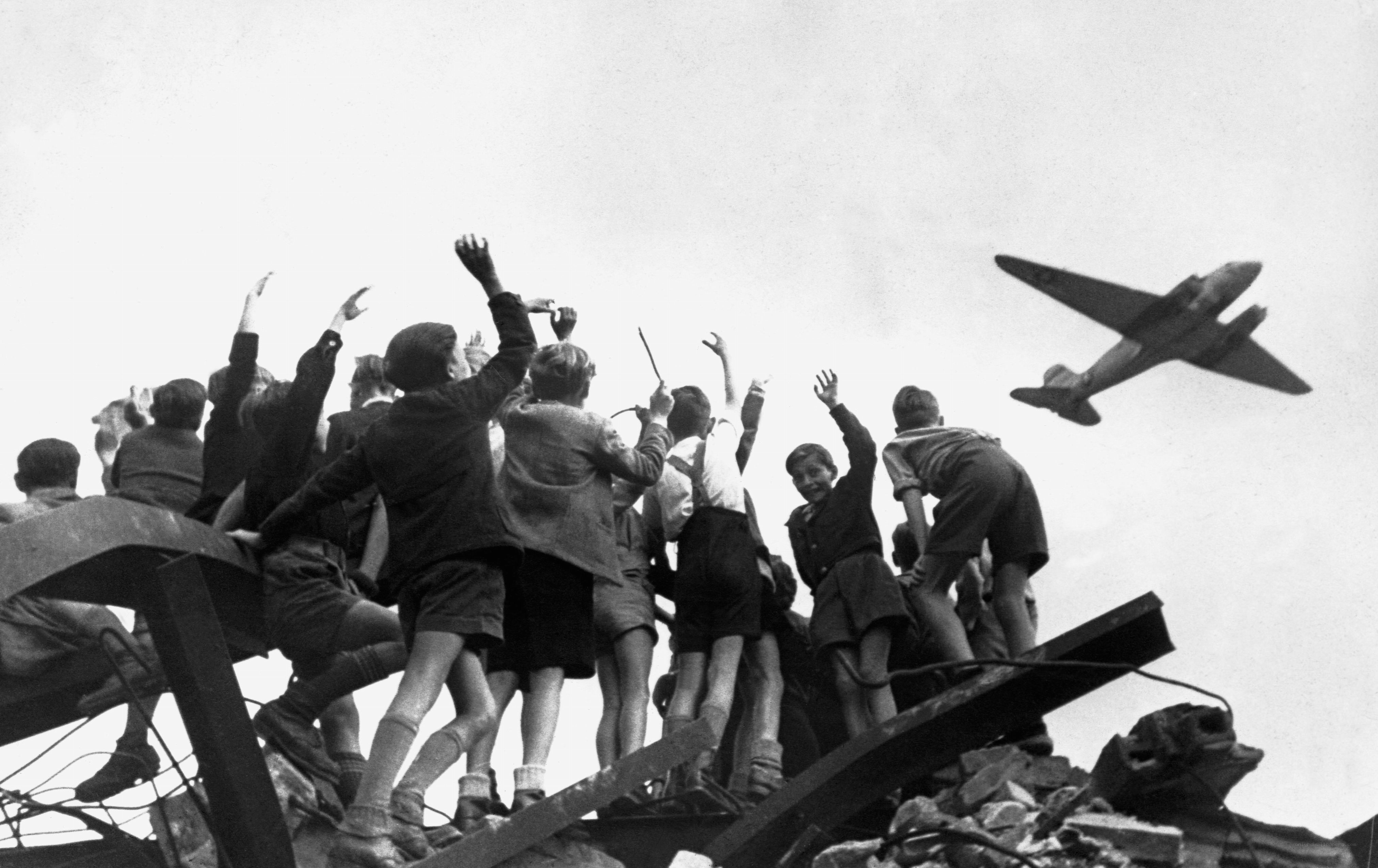 Children on rubble watching plane