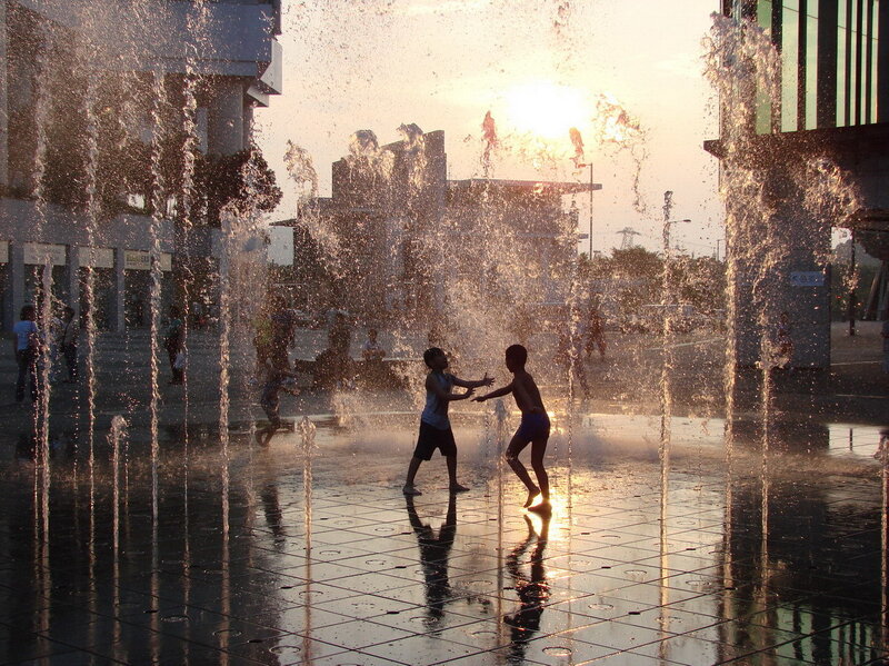 Children playing in a fountain at sunset