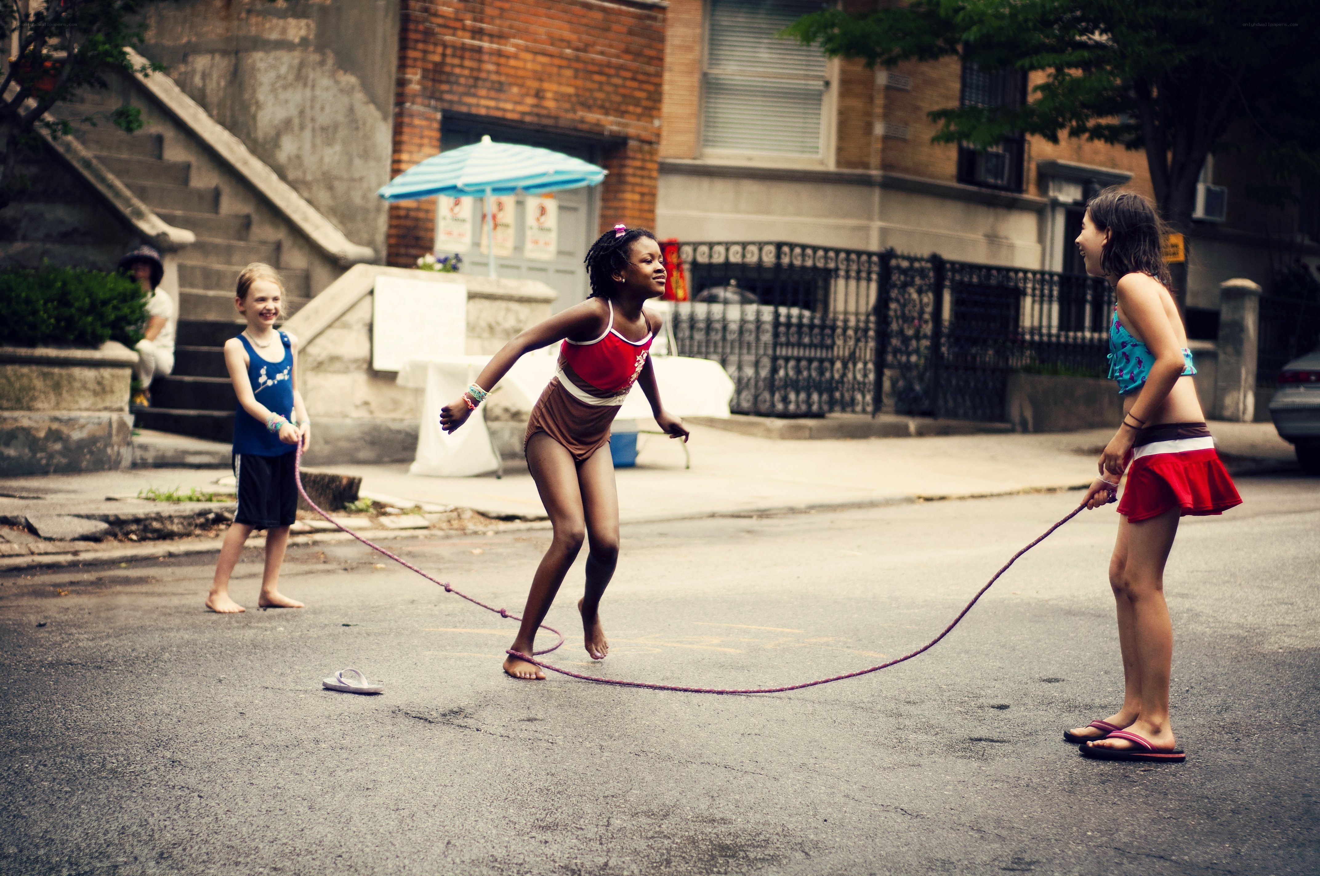 Children playing jump rope on street