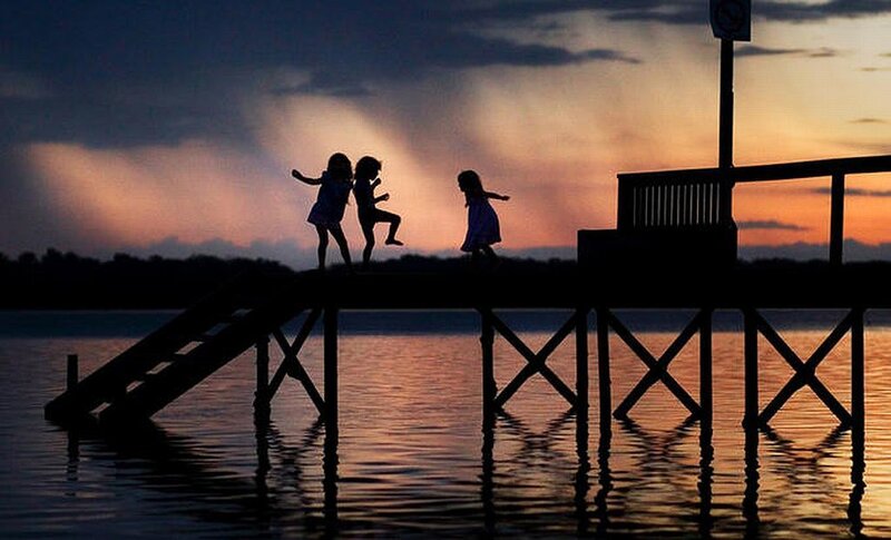 Children playing on a dock at sunset