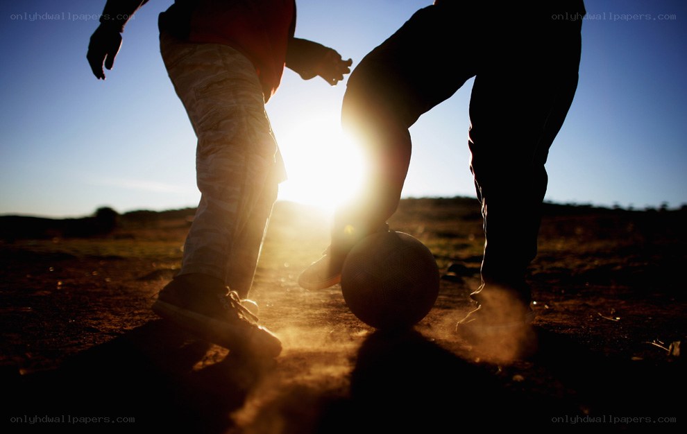 children playing soccer at sunset