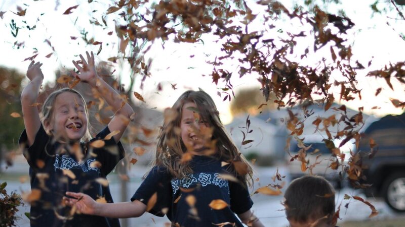 Children playing with autumn leaves