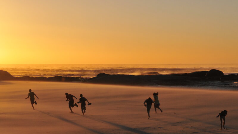 Children running on beach at sunset