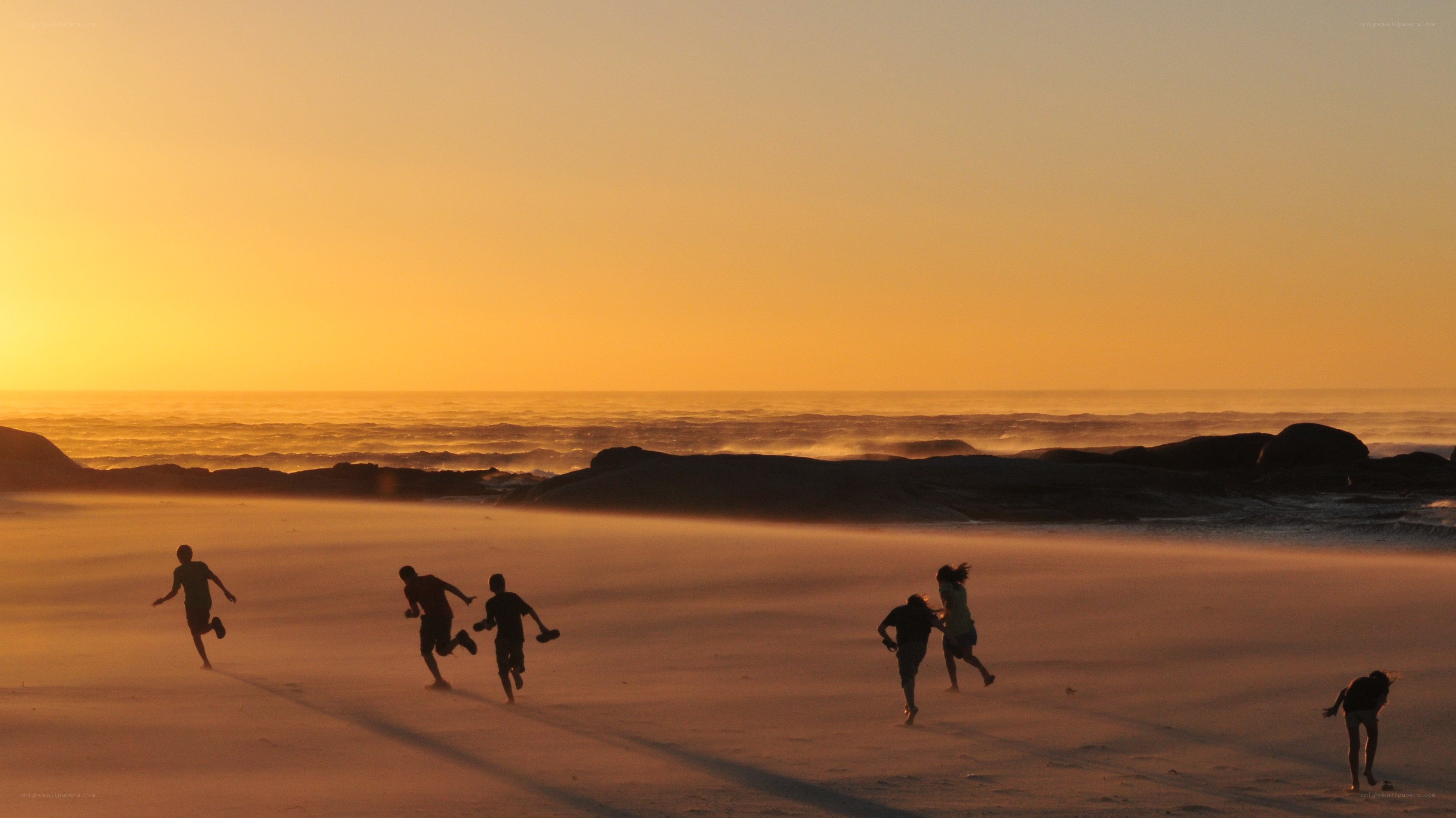 Children running on beach at sunset