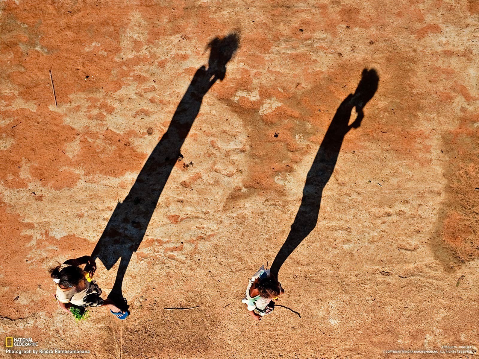 Children's shadows on red earth