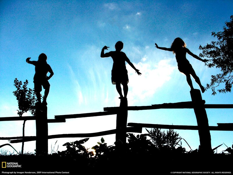 Children silhouetted on a fence