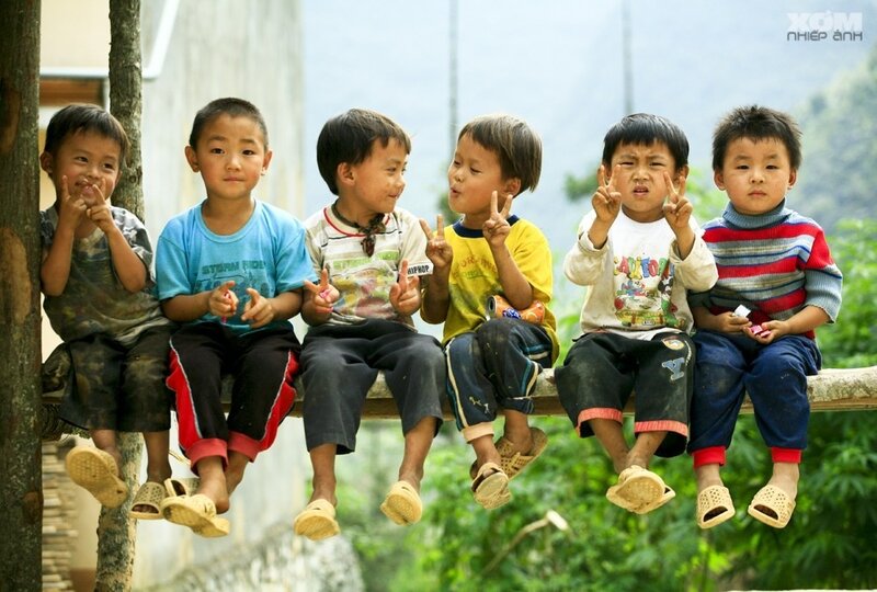 Children sitting on a wooden beam