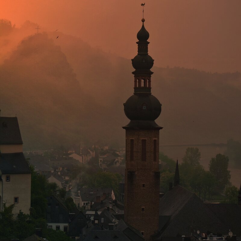 Church tower at sunset in a misty town