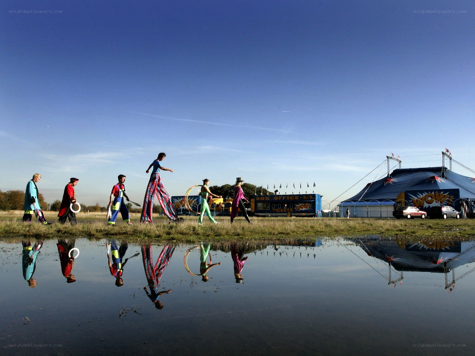 Circus performers walk by a tent