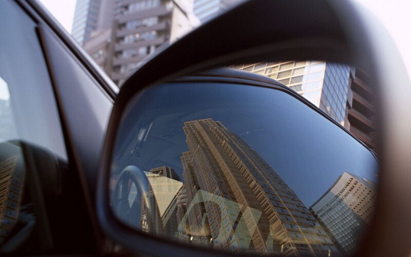 City buildings reflected in car mirror