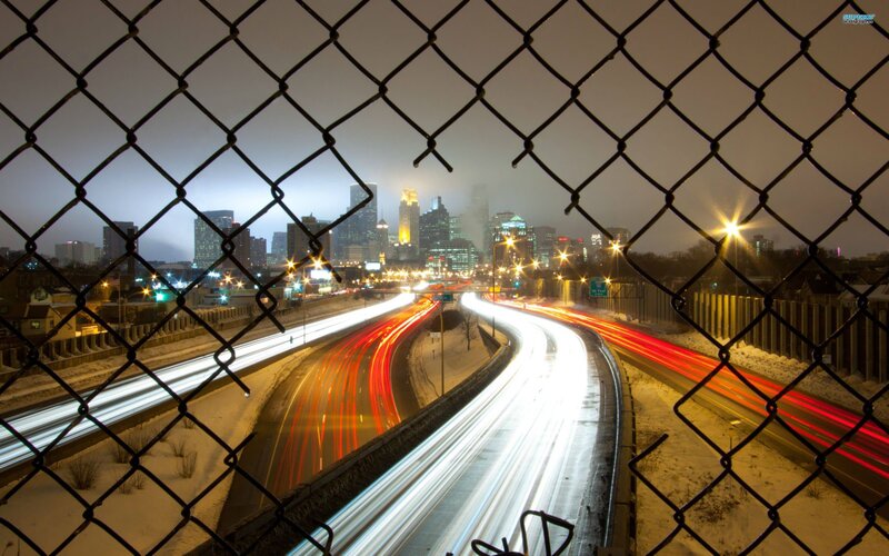 City highway at night through fence