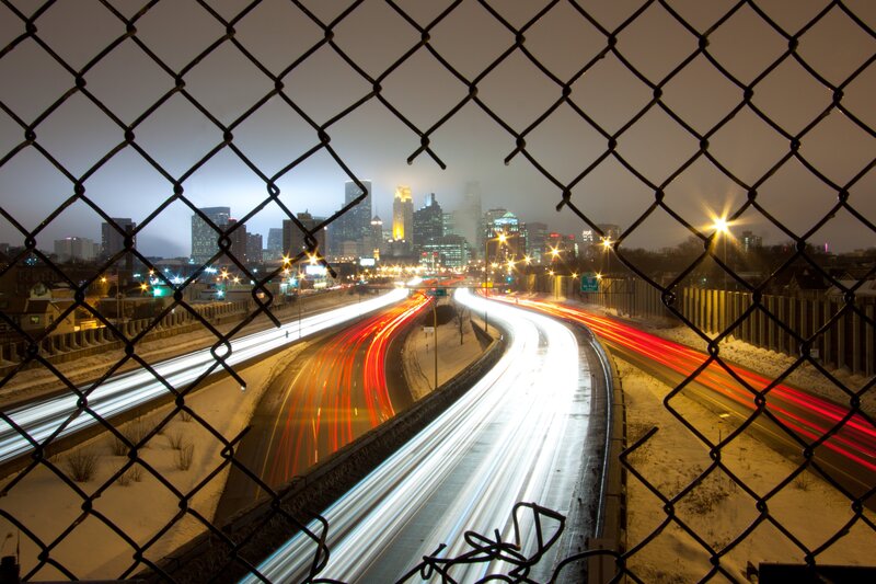 City highway at night through fence