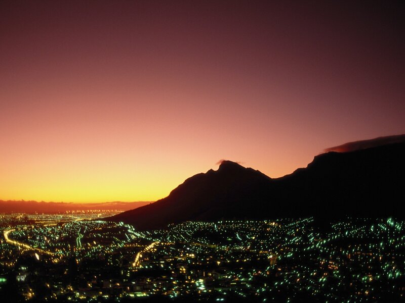 City lights at dusk with mountain silhouette