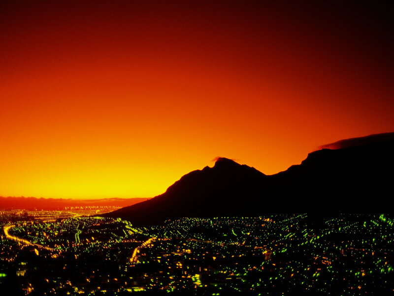 City lights at sunset with mountain silhouette