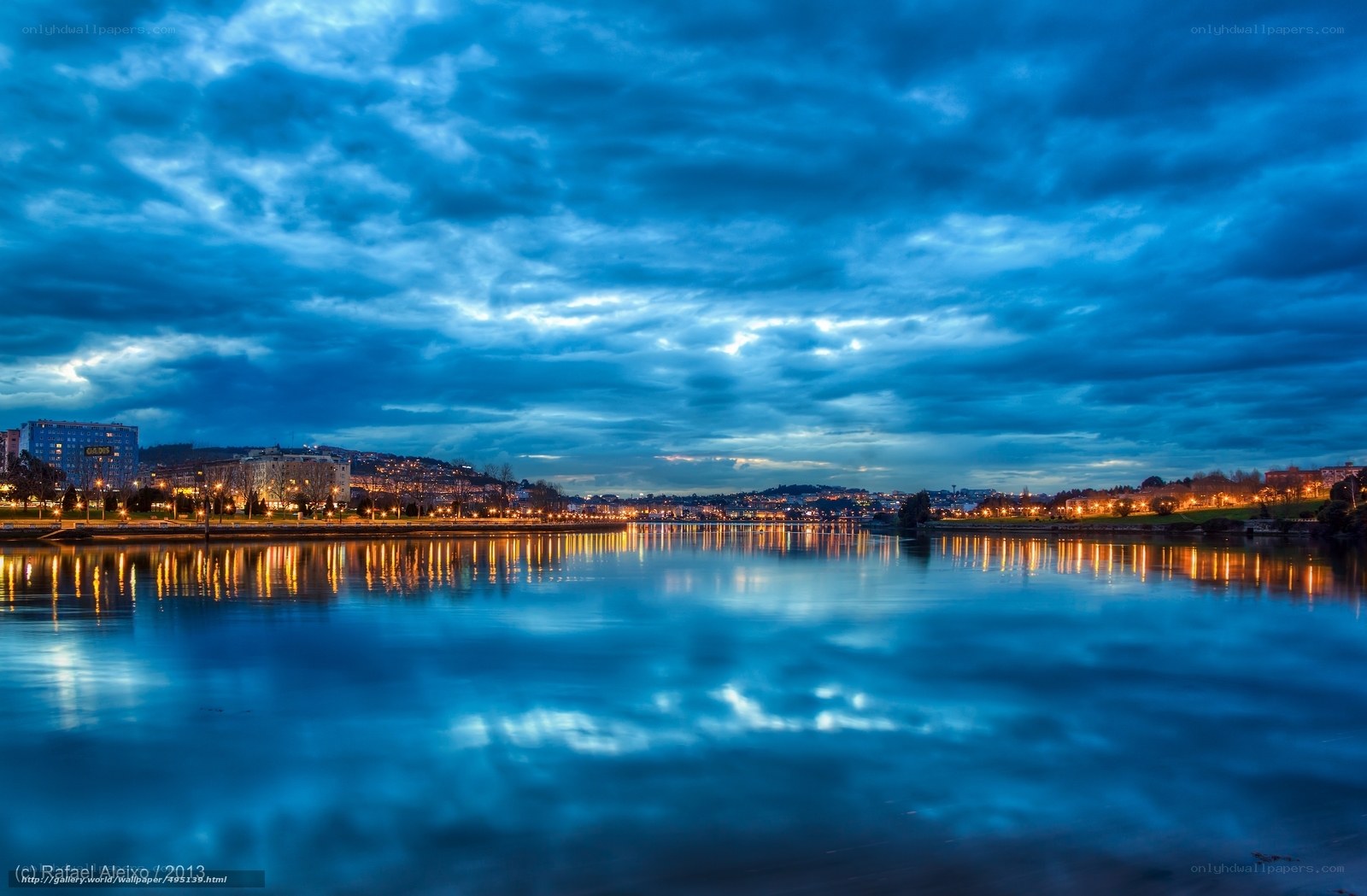 City lights reflect on river at dusk