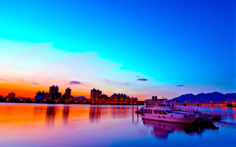 City Skyline at Dusk — Blue, Serene, Sunset, Photograph, River, Boat