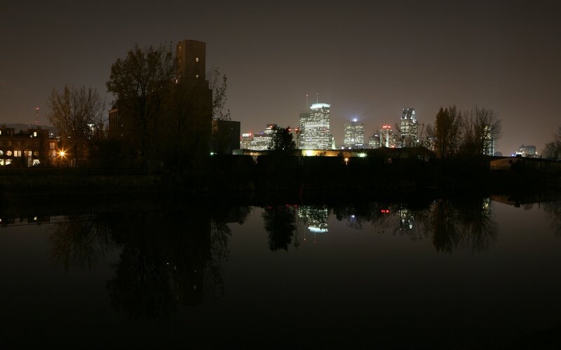 City Skyline at Night — Black, Calm, Photograph, Buildings, River, Trees