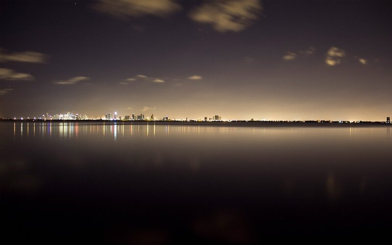 City Skyline at Night — Black, Serene, Photograph, Water, Clouds