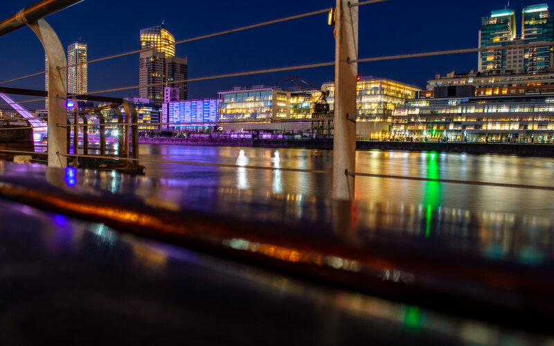 City Skyline at Night — Blue, Calm, Photograph, River, Buildings, Railing