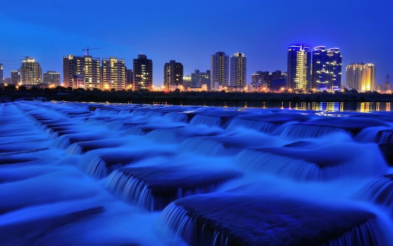 City skyline at night with waterfalls